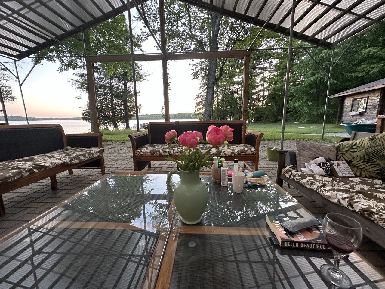 The covered lakeside deck with lounge seating and water views