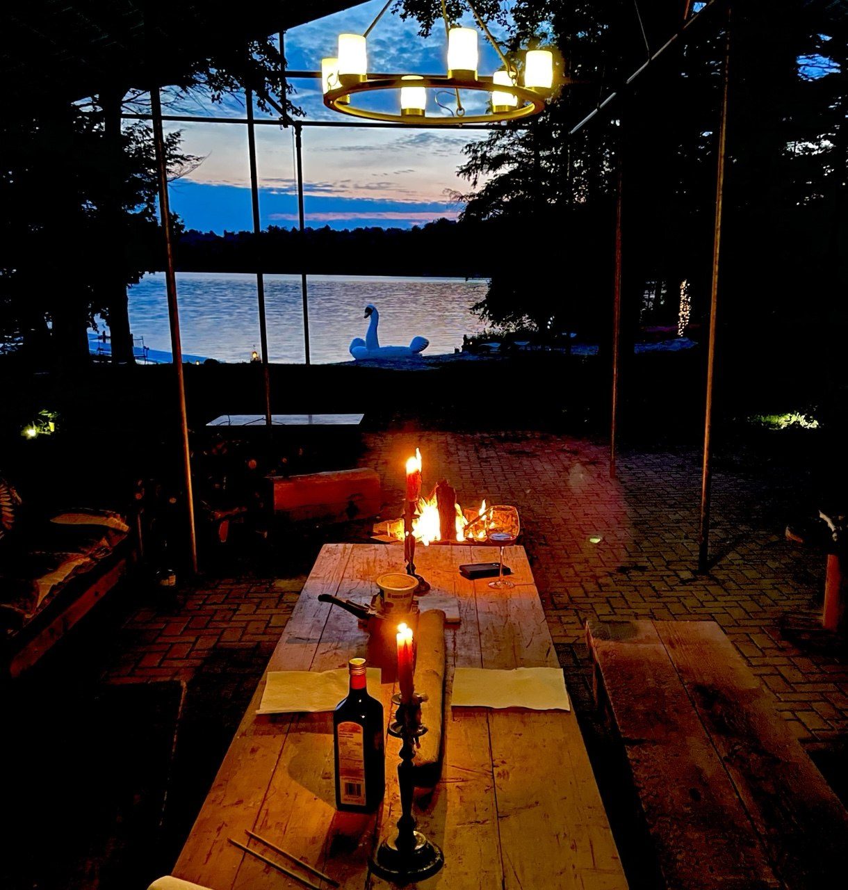 A long table set for dinner under the lakeside pavilion at dusk